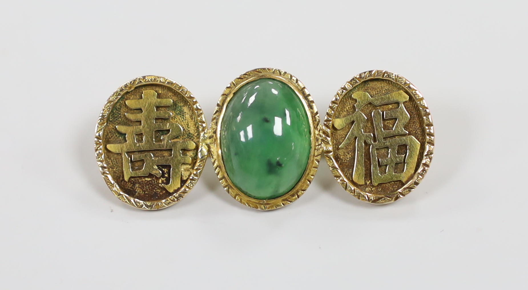 A Chinese yellow metal and cabochon jade and Chinese character set triple oval motif brooch, 39mm, gross weight 6.2 grams.